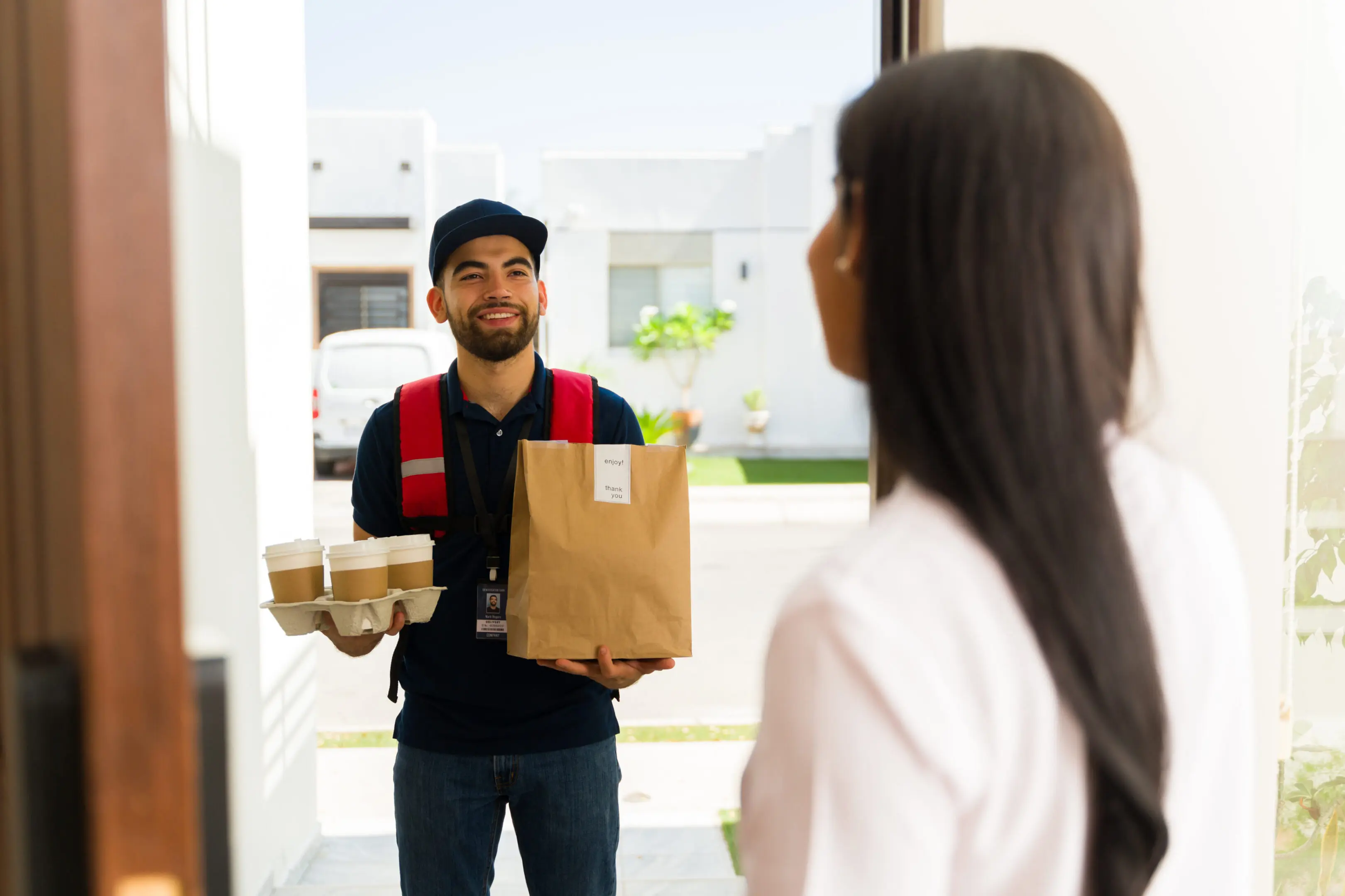 A man holding food and wearing a red vest.